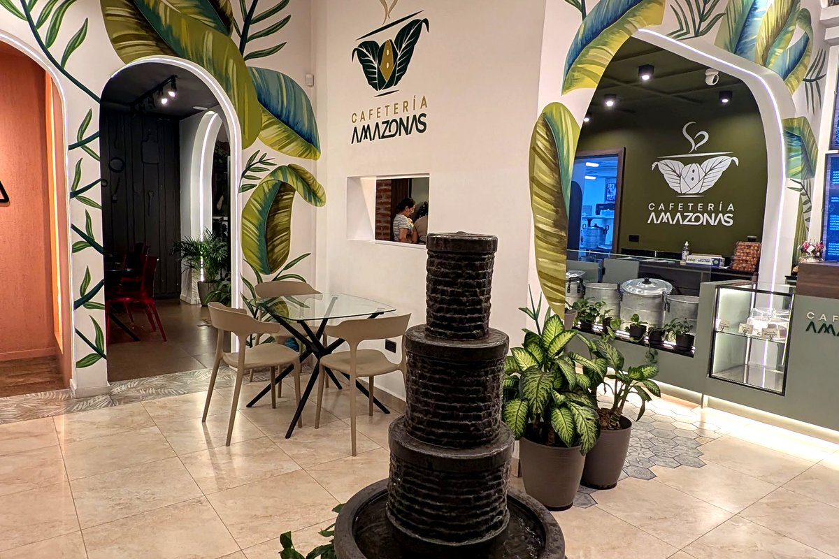 Entrada de Cafetería Amazonas en Cumbayá con fuente de piedra, plantas y murales tropicales
