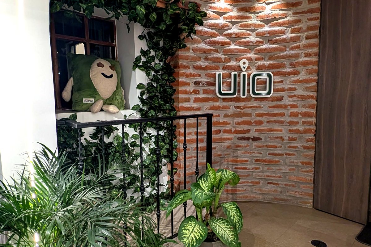 Rincon UIO con letrero neon, pared de ladrillo y plantas